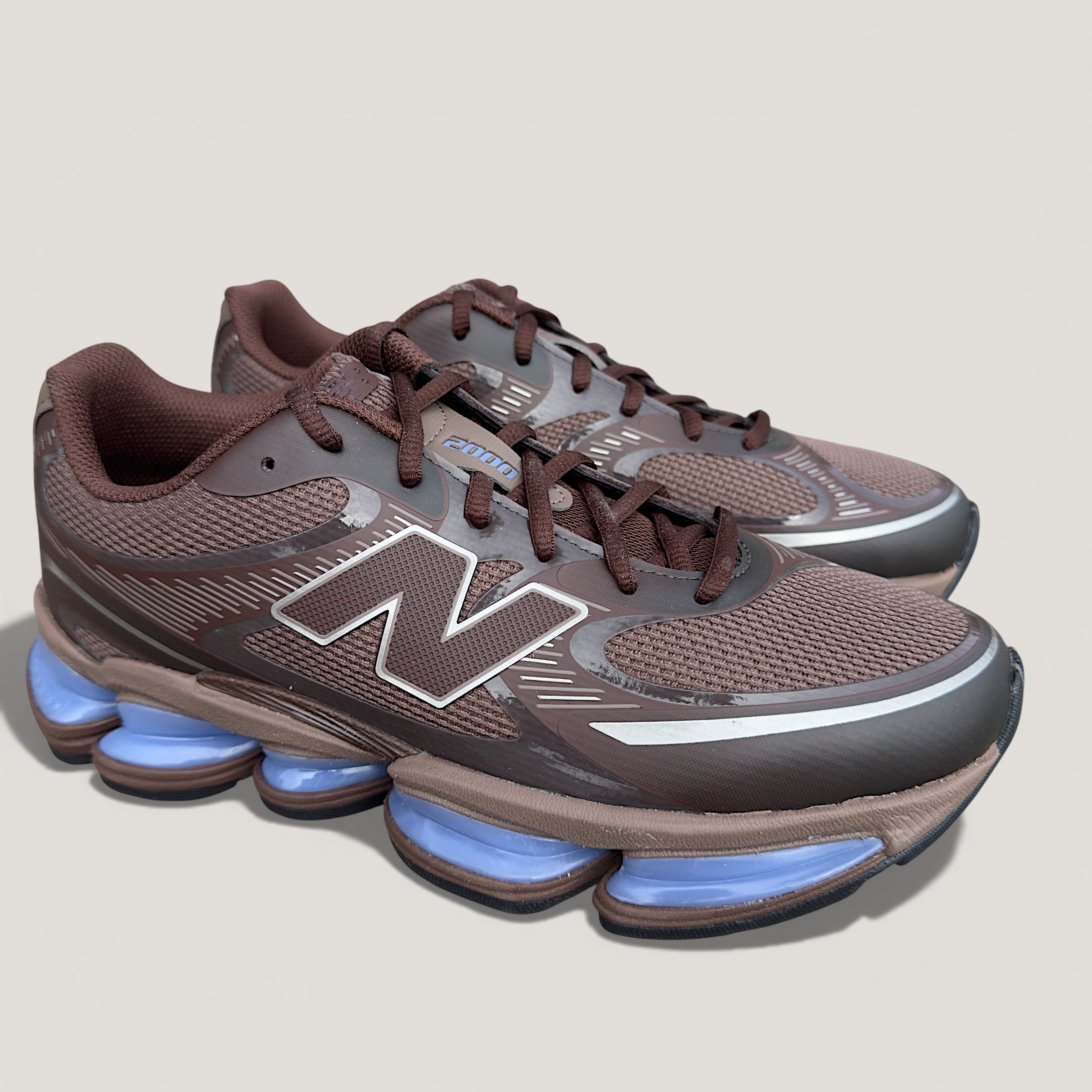 New Balance brown sneakers with mesh upper and unique blue cushioned soles, footwear fashion