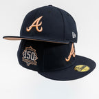 A black Atlanta Braves 150th anniversary fitted baseball cap by New Era, featuring a tan leather-look 'A' logo on the front and side, a gold 150th anniversary patch on the brim, and a gold New Era logo on the side.