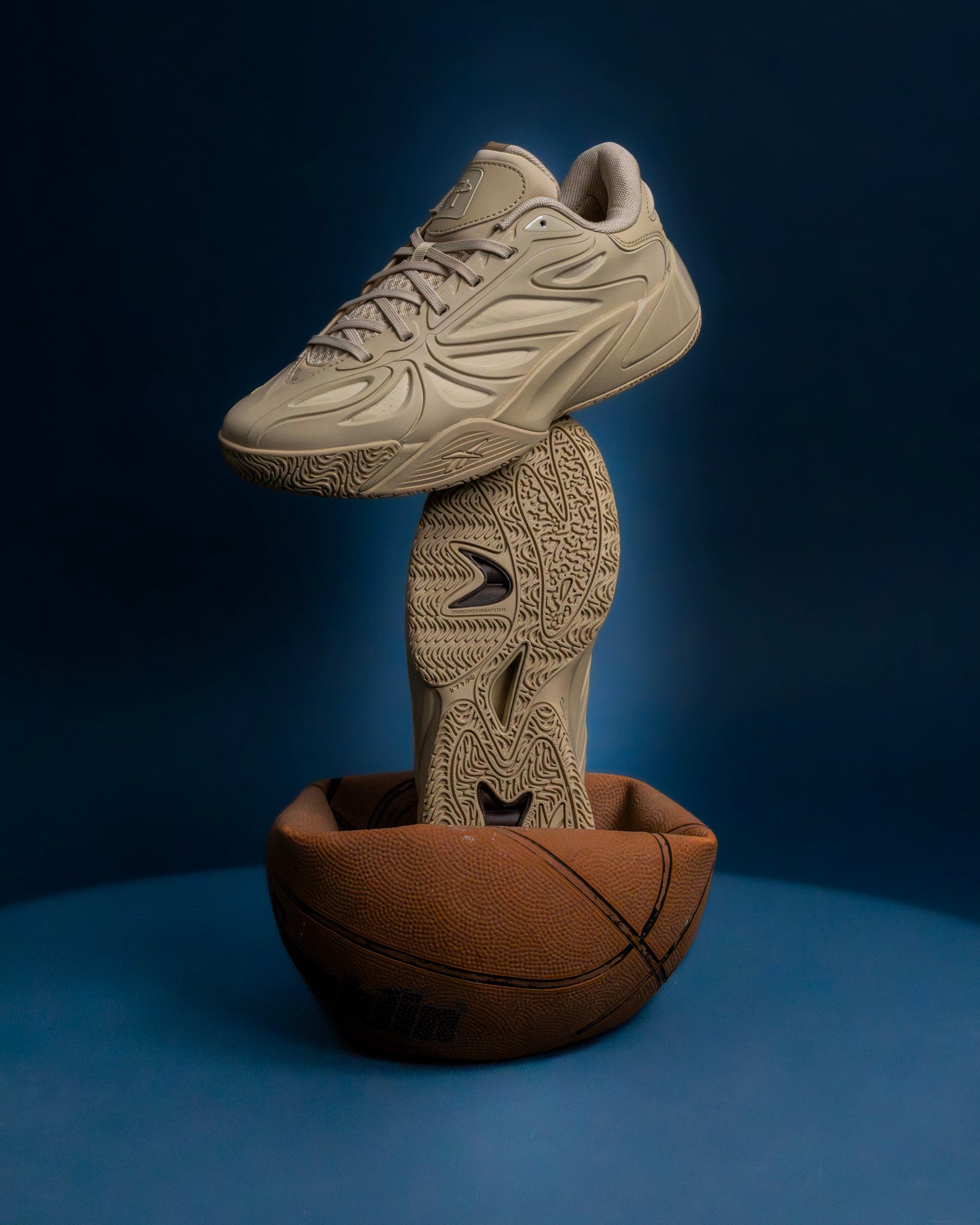 Tan new balance sneaker displayed above a basketball, stylish footwear against blue background.