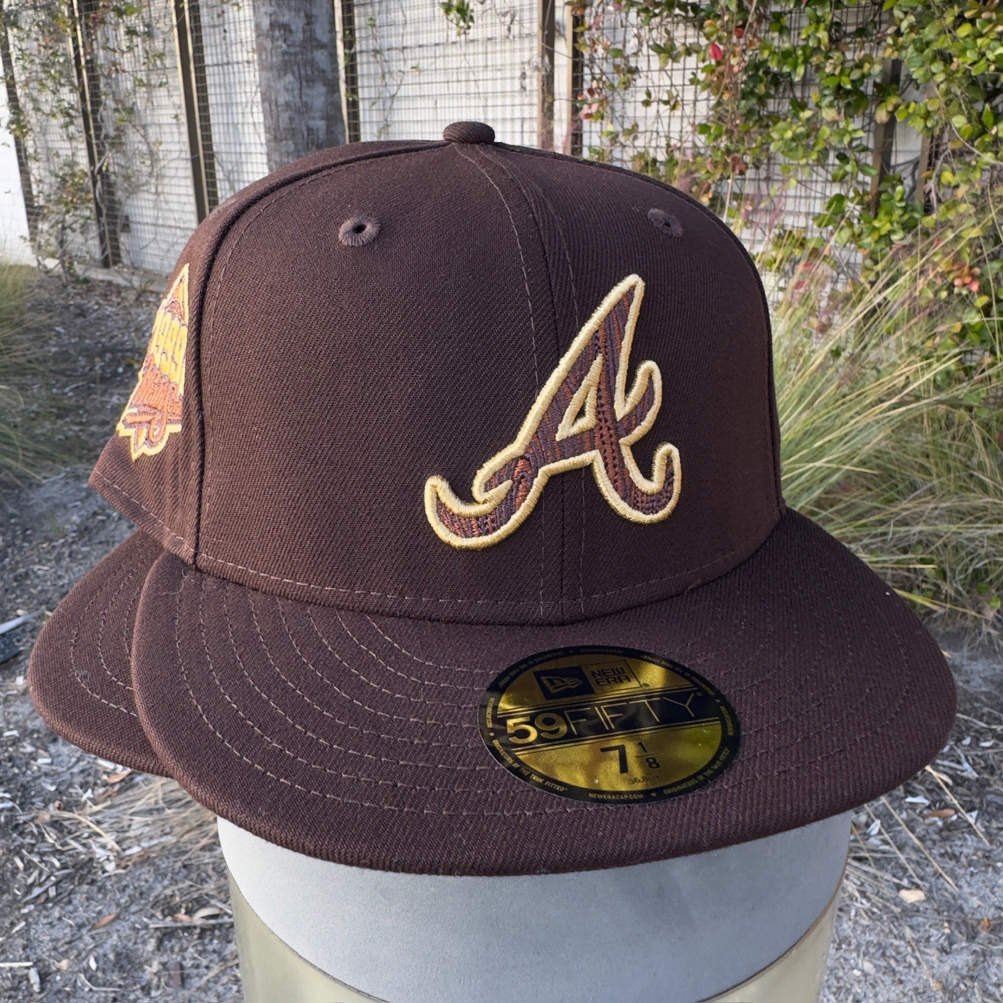 brown New Era fitted cap with Atlanta A logo and commemorative side patch, outdoors