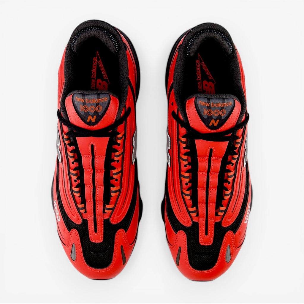 Top view of New Balance 1000 orange sneakers, black mesh upper, premium footwear.