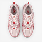 Pink and white New Balance sneakers with red accents, mesh and suede running shoes, top view