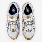 New Balance sneakers in white, gold, and blue with mesh upper, viewed from above.