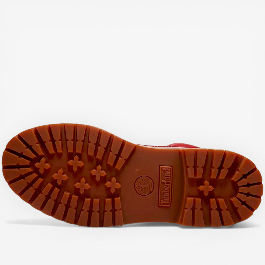 Close-up of a red boot sole with tread pattern on a white background
