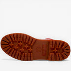 Close-up of a red boot sole with tread pattern on a white background