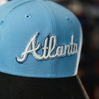 METRO Atlanta Braves blue fitted hat with white embroidered 'Atlanta' script and grey UV underbrim. New Era 59FIFTY silhouette.