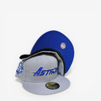New Era fitted cap in grey and blue with Astros logo, anniversary patch, and baseball graphic under brim.