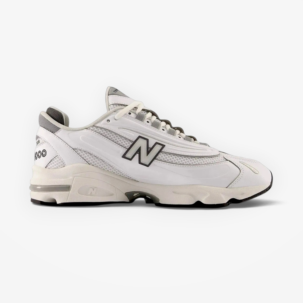 new balance white sneaker with mesh and leather panels, grey accents, side profile on black background
