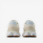 Beige New Balance sneakers viewed from the back, suede and mesh upper, rubber sole.