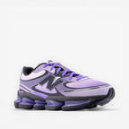 Purple New Balance sneaker with black and grey accents, athletic footwear on black background