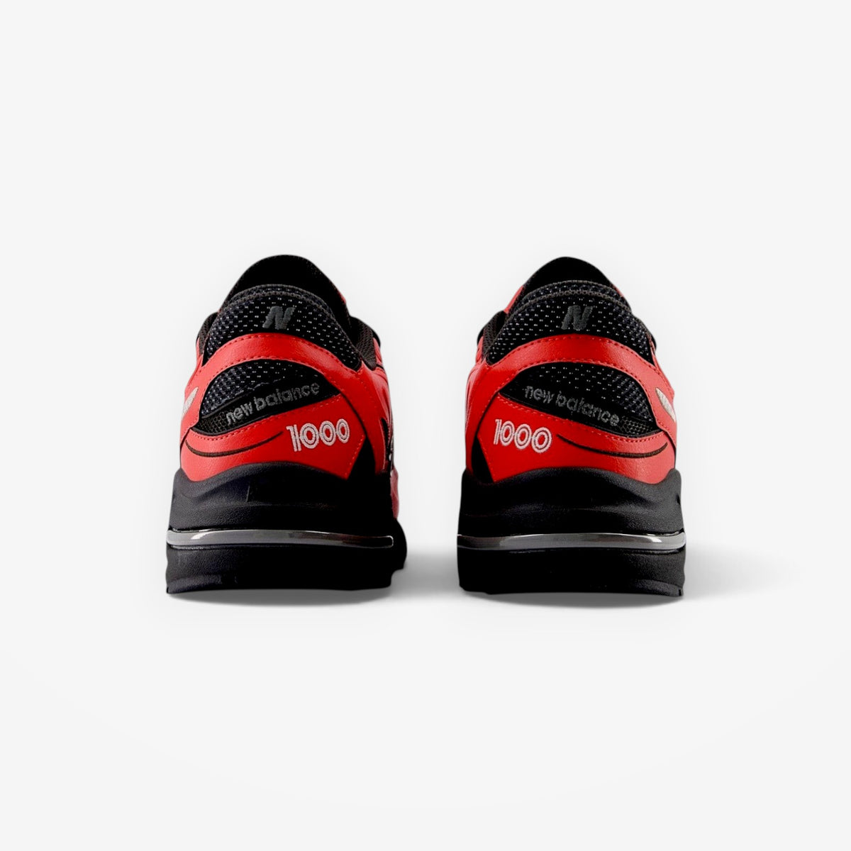 METRO New Balance M1000 sneakers in red and black, showing the rear view with 1000 branding and segmented sole unit.