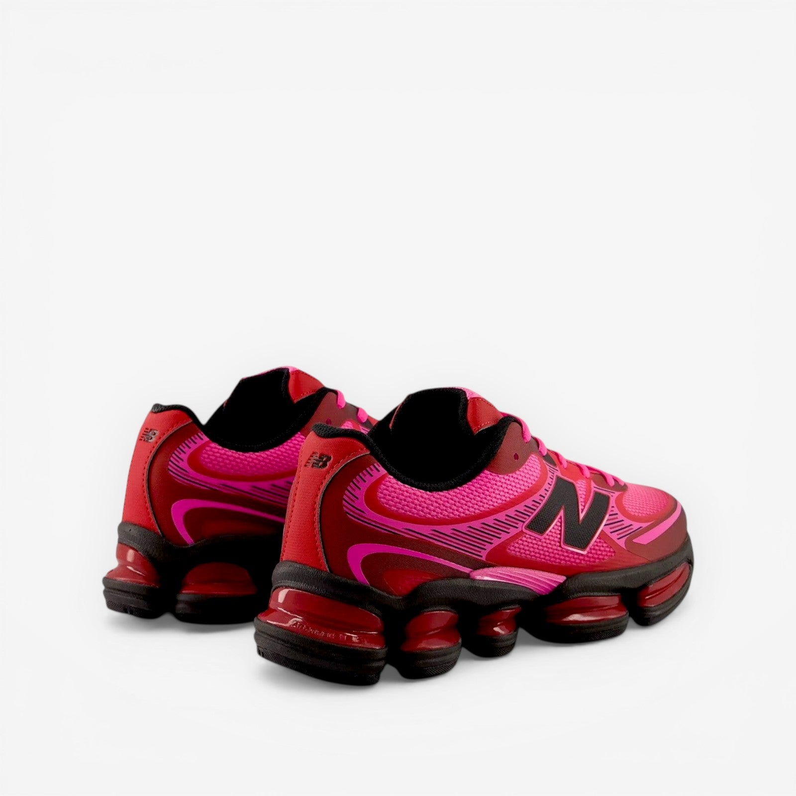 Red and pink running shoes with black soles on a white background