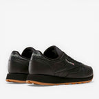 METRO Reebok Classic Leather black leather sneakers with grey accents and gum sole. Low-top lace-up style.
