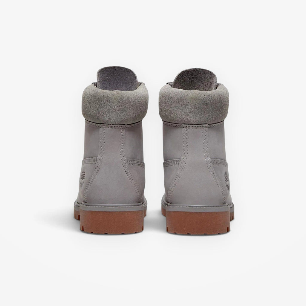 Rear view of METRO Timberland Premium 6-Inch waterproof boots in medium grey nubuck with brown rubber lug soles.